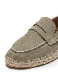 Mocasines de ante verde claro con costuras decorativas, punta redondeada y suela de cuerda de yute. Detallados con un acento de cuero en el empeine.