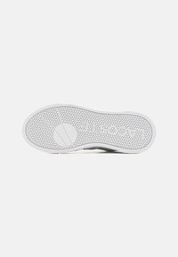 White sneaker sole with hexagonal texture, featuring a circular emblem. Designed with a curved shape and minimal accent details.