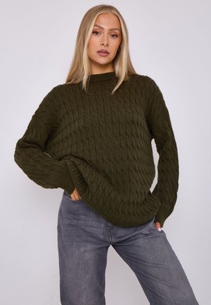 Chandail en tricot d'un vert olive foncé avec un design de câble texturé, doté d'un col haut et de manches longues légèrement surdimensionnées.