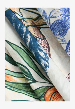 Lillemustriga kangas, kus on rohelist lehte ja siniseid lilli helebeeži taustal, mis näitab siledat tekstuuri ja kihilist drapeeringut.