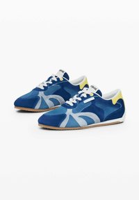 Sneakers din suede albastru cu un design unic, cu accente de albastru deschis și alb, vârf rotund, șireturi albe și un tab de călcâi galben.