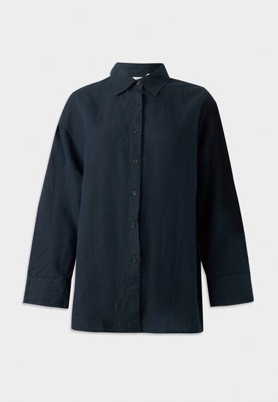 Μαύρο πουκάμισο με μακριά μανίκια, κουμπιά, γιακά, δομημένες μανσέτες και ίσιο τελείωμα, εμφανισμένο σε λευκό φόντο.