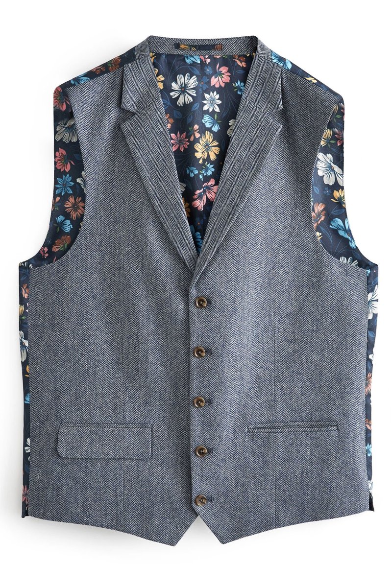 Kamizelka w szarym kolorze o wzorze jodełki, z niebieskim wnętrzem w kwiatowy wzór. Posiada pięć guzików i dwie boczne kieszenie. Bez rękawów.