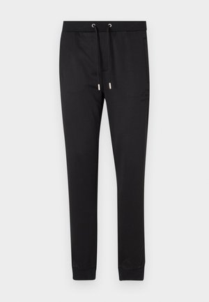 Pantalons de jogging noirs en tissu doux, présentant une taille élastique avec cordons de serrage, des poches latérales et des poignets ajustés aux chevilles.