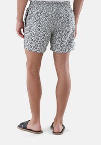 Badehose mit Blumendruck in Marineblau und Weiß, aus leichtem Stoff. Mit elastischem Bund und seitlichen Taschen.