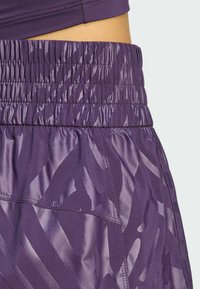 Lila Sportshorts mit einem gerafften, elastischen Bund und einem glatten, strukturierten Stoff mit einem subtilen, abstrakten Muster.