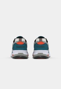 Para zielono-niebieskich, białych i pomarańczowych sneakersów Reebok pokazanych z tyłu na białym tle.