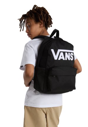 Svart tygryggsäck med en stor vit "VANS"-logotyp, en framficka och justerbara remmar. Bår av ett barn i en vit T-shirt.