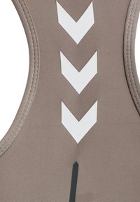 Gros plan sur un tissu beige avec trois flèches blanches vers le bas et un détail de bande verticale noire sur un matériau texturé.