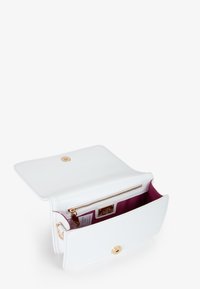Witte leren handtas met gouden hardware, ritsvak en een paarse binnenkant. Klep sluiting met een decoratieve knop. Compact rechthoekige vorm.