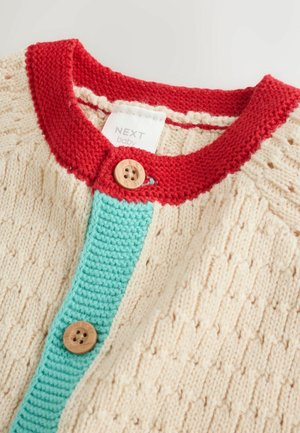 Cremefarvet strikket cardigan med rød krave, turkis knapstolpe og træknapper med et tekstureret mønster på kroppen.