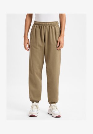 Khaki jogger pants made of soft fabric, featuring an elastic waistband, side pockets, and elastic cuffs at the ankles. Embroidered logo detail.