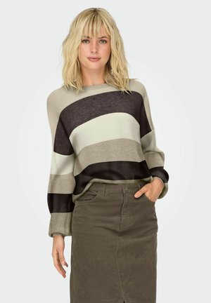 Brede gestreepte gebreide trui in tinten van beige, olijfgroen en donkerbruin; gecombineerd met een bijpassende olijfgroene corduroy rok.