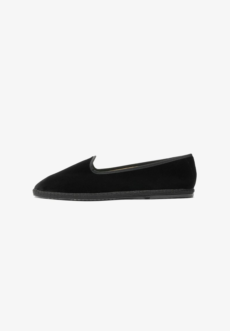 Zapato de ante negro tipo slip-on con superficie lisa, punta redondeada y ribete elástico alrededor de la abertura. Cuenta con una suela de goma de perfil bajo.