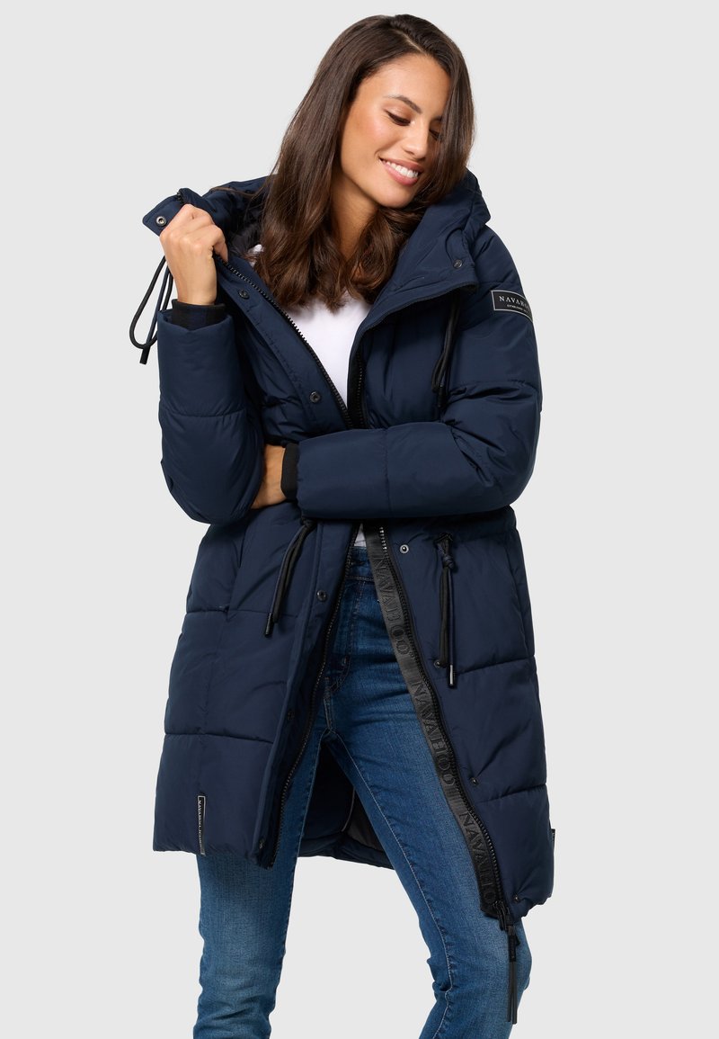 Navy blue puffer coat with a hood, features adjustable drawstrings, a full front zipper, and a logo patch on the sleeve. Textured quilted design.