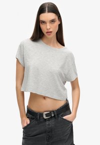 Geknipte grijze t-shirt van een zachte, gestructureerde stof met korte mouwen en een ruime halslijn, gecombineerd met high-waisted zwarte denim jeans en een riem.