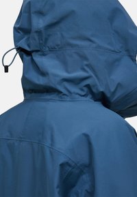 Hooded jack in donkerblauw, gemaakt van glad, waterafstotend materiaal. Heeft een verstelbare trekkoord en subtiele naaddetails.