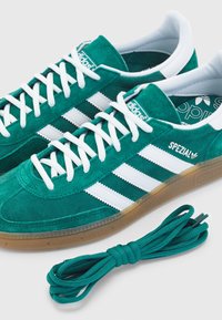 Gröna mockaskor för sport med vita ränder och logotyp. Med gummisulor och extra matchande skosnören.