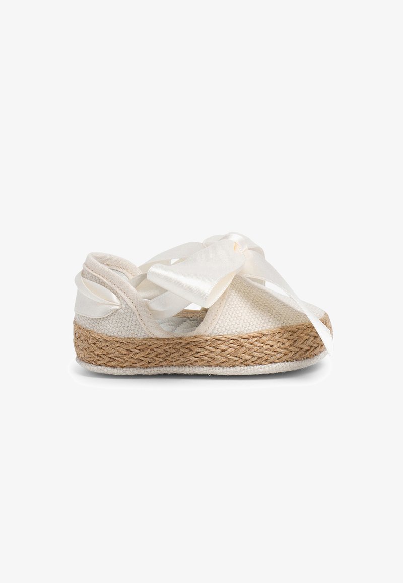 White woven canvas shoe with a jute outsole, featuring a large satin ribbon bow on the front and crisscross straps for secure fit.
