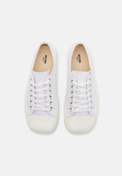 Vita canvas sneakers med rund tå, platta snören, metallöglor och gummisulor. Texturerat tyg med minimal stilmarkering på innersulan.