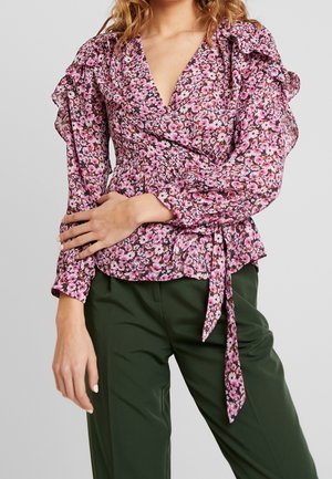 Blumenmusterbluse mit rosa und weißen Blumen auf dunklem Hintergrund. Verfügt über Rüschensäume, V-Ausschnitt und eine Krawatte in der Taille.