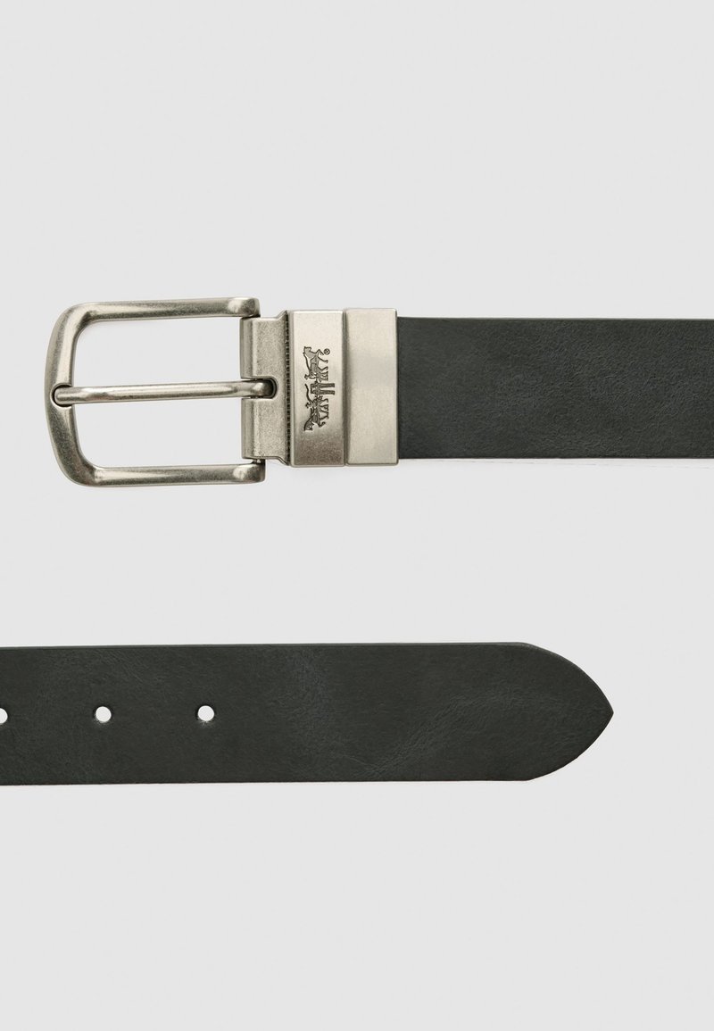 Sort læderbælte med en sølvfarvet metalbuckle i rektangulær form og en glat overflade. Indeholder huller til justering.