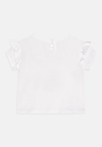 Camisa blanca de manga corta con acentos de volantes, con un cuello redondo y cierre de botón en la parte posterior. Hecha de material de algodón suave.