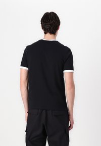 Czarny T-shirt z krótkim rękawem, okrągłym dekoltem i białym wykończeniem przy rękawach oraz kołnierzu. Miękki materiał o luźnym kroju.