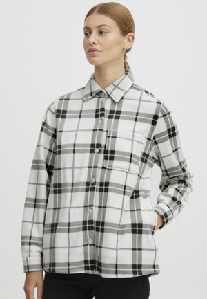Plaid fleece shirt in white, gray, and black. Features a button-down front, chest pocket, and long sleeves with a relaxed fit.