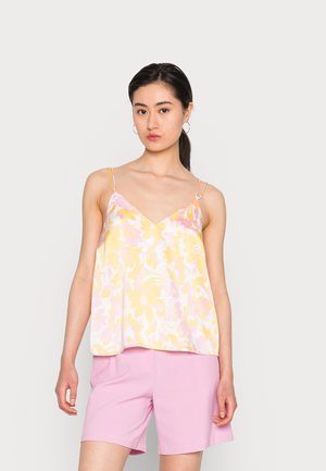 Camisola floral em amarelo e rosa, com alças finas e decote em V. Usada com calções rosa claros, exibindo um corte solto e tecido suave.