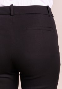 Zwarte op maat gemaakte broek van textuurstof met een rechte snit, voorzien van een achterzakdetail en riemlussen.