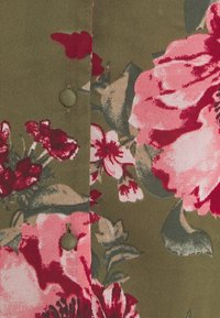 Tessuto a trama floreale in verde oliva con grandi fiori rosa e rossi, dotato di chiusura a bottone e texture morbida e liscia.