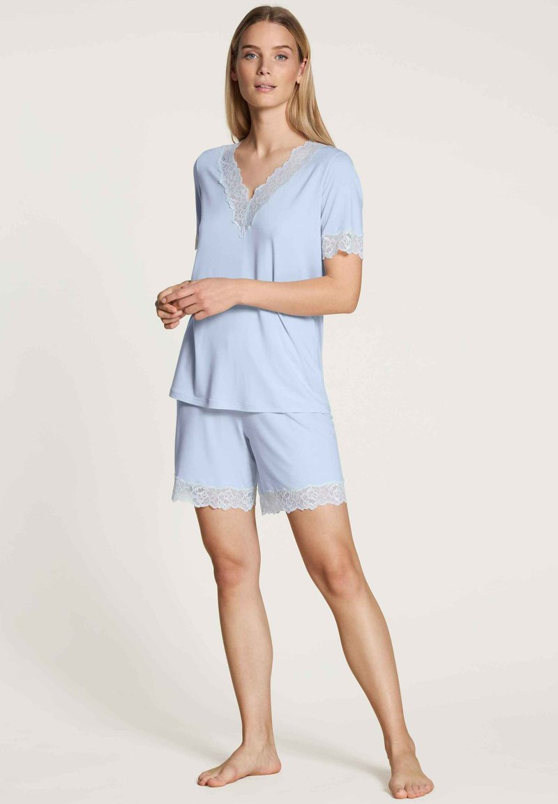 Lichtblauwe korte pyjama set met een kanten rand op de mouwen en shorts. Zacht materiaal, ontspannende pasvorm, met een V-hals ontwerp.