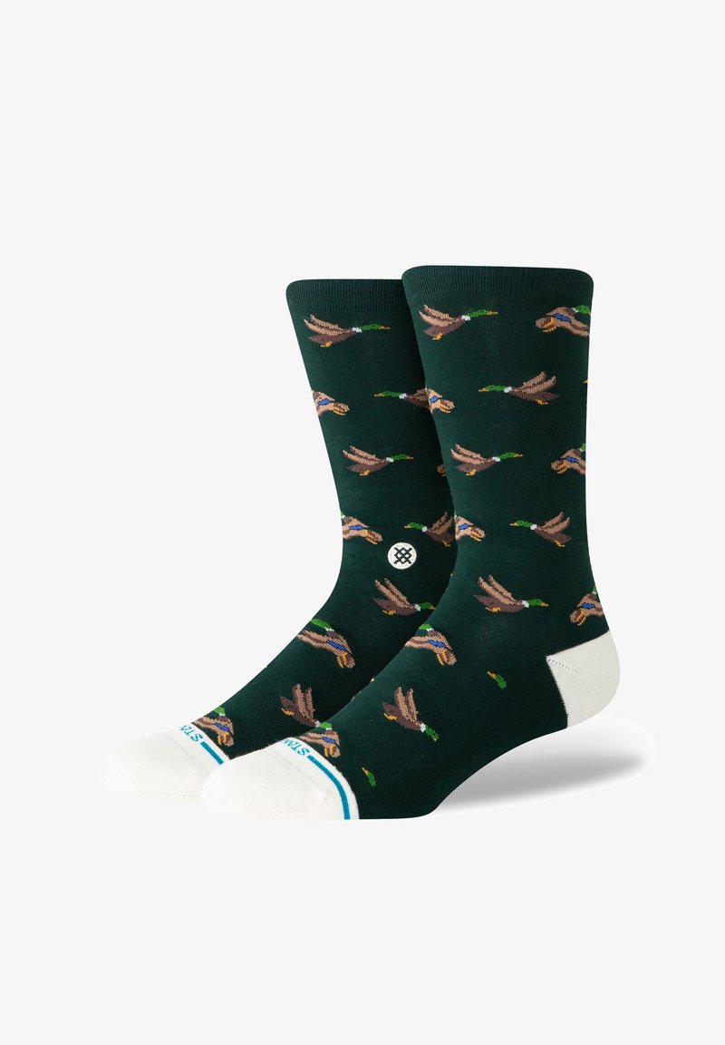 Calcetines verdes con un patrón repetido de patos voladores, con acentos en el puntera y talón reforzados en blanco, y una banda a rayas en la parte superior.