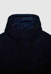 Marineblaue, strukturierte Kapuzenjacke mit einer puffigen Innenlage, die einen hohen Kragen und verstellbare Zugbänder an der Kapuze aufweist.