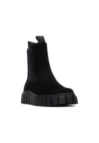 Stivaletti alla caviglia in suede nero con suola spessa e testurizzata, pannelli laterali elasticizzati e linguette per facilitarne l'indossamento. Design minimalista, finitura liscia.