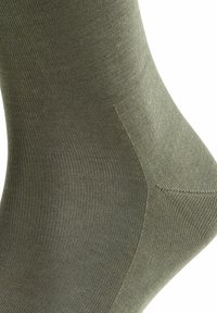 Calzino verde oliva realizzato in materiale liscio e elasticizzato. Presenta una texture a coste e un rinforzo al tallone e alla punta per una maggiore durata.