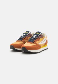 Orange and brown sneakers with suede and mesh materials, featuring a white logo, black sole, and blue laces. Collapsible tongue design.