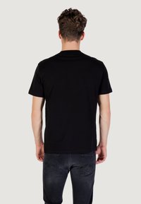 T-shirt nero a maniche corte realizzato in cotone. Design semplice con collo a giro, texture liscia e opaca, senza motivo o logo visibili.