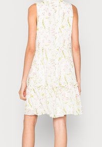 White floral dress with pink and green patterns, sleeveless design, cinched waist, and ruffled hem, made from lightweight fabric.