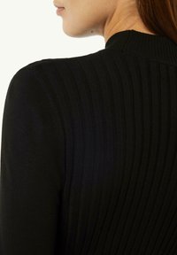 Schwarzer gerippter Pullover mit rundem Halsausschnitt und strukturiertem Stoff, mit vertikalen Streifen, die ein dezentes Muster entlang des Rückens bilden.