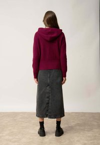 Burgundy-huppari, jossa on teksturoitu pinta, yhdistetty mustaan denimi-midi-hameeseen, jossa on keskiväli, ja mustat platform-kengät.