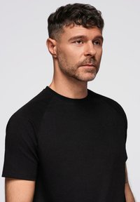Sort kortærmet t-shirt lavet af blødt stof, med rund halsudskæring og raglanærmer, med minimal syning og en glat tekstur.