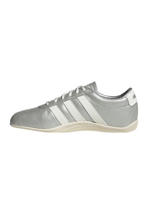Grauer Adidas Sneaker mit weißen Streifen, flacher Sohle und Schnürsenkeln, von der Seite auf weißem Hintergrund gezeigt.