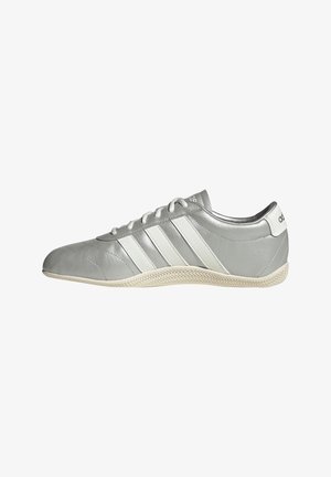 Grauer Adidas Sneaker mit weißen Streifen, flacher Sohle und Schnürsenkeln, von der Seite auf weißem Hintergrund gezeigt.
