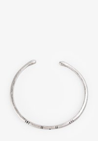 Pulsera de brazalete de plata con forma suave y redondeada y una textura sutil. Presenta muescas y líneas como acentos decorativos.