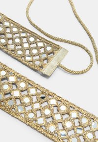 Goudkleurige gevlochten riem met vierkante en ronde spiegelachtige versieringen op een witte ondergrond.