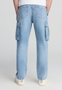 Pantaloni cargo in denim azzurro chiaro con vestibilità rilassata, dotati di due tasche laterali, due tasche posteriori e gamba dritta.