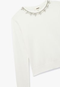Maglione bianco con scollatura rotonda impreziosita da una collana di strass e maniche lunghe, realizzato in un morbido tessuto testurizzato.