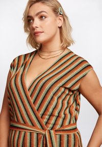 Top met korte mouwen, met horizontale strepen in oranje, groen en zwart. Geverfde stof met een knoopdetail in de taille.